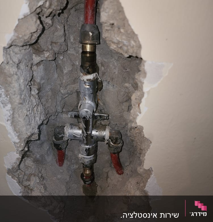 צנרת מים חשופה בקיר עם חיבורים וברזים